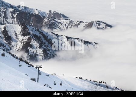 Skigebiet in Bewölkt Tian Shan Berge im Nebel. Skilift auf der Piste. Stockfoto