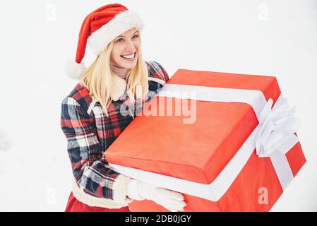 Santa Frau hält eine große Geschenkbox mit Kopieplatz für Ihren Text. Christmas Girl hält ein großes Geschenk. Große Geschenkbox. Verrückte Weihnachten Mädchen schiebt ein großes gif Stockfoto