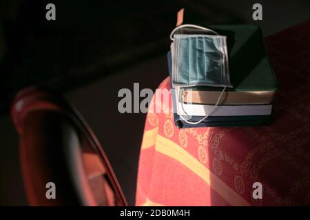 Gesichtsmaske auf gestapelten Büchern auf dem Tisch. Studie während des Pandemiekonzepts. Stockfoto