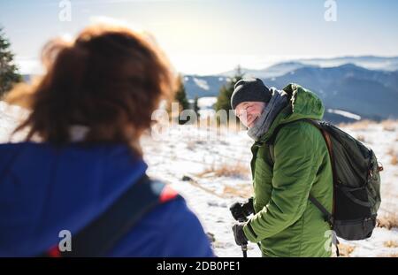 Ältere Wanderpaare mit nordic Walking Stöcken in schneebedeckter Winternatur. Stockfoto