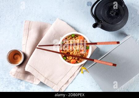 Ramen Tasse. Instant Nudeln in einer Plastikbecher, von oben mit Tee und ein Buch geschossen. Asiatisches Mittagessen Stockfoto