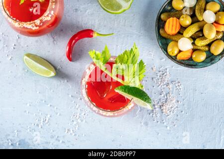 Bloody Mary Cocktail, Tomatensaft mit Alkohol, Top Shot mit Gurken. Die Gläser sind mit Limette und Sellerie garniert Stockfoto