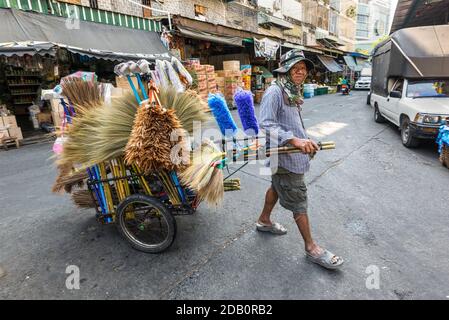 Bangkok, Thailand - 7. Dezember 2019: Straßenverkäufer von Besen und Federdustern reist eine Straße mit dem Wagen voller Waren - Verkauf fegenden brus Stockfoto