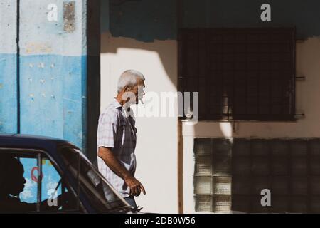 Mann mit Zigarre läuft im Zentrum von Havanna. Kubanische Straßenszene. Stockfoto