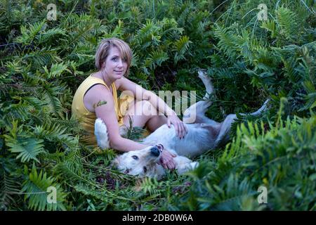 Blonde Dame liebt ihren Golden Retriever Hund im Wald Stockfoto