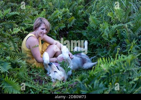 Blonde Dame liebt ihren Golden Retriever Hund im Wald Stockfoto