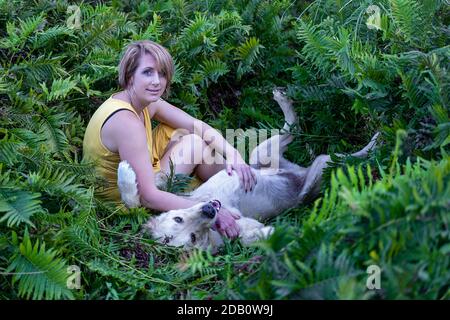 Blonde Dame liebt ihren Golden Retriever Hund im Wald Stockfoto