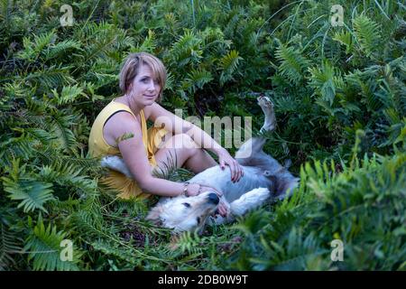 Blonde Dame liebt ihren Golden Retriever Hund im Wald Stockfoto