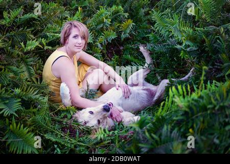 Blonde Dame liebt ihren Golden Retriever Hund im Wald Stockfoto