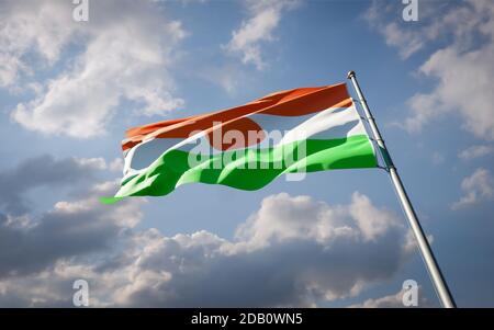 Schöne Nationalflagge von Niger flattert am Himmel Hintergrund. Nahaufnahme der Niger-Flagge mit niedrigem Winkel und 3D-Grafik. Stockfoto