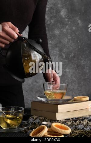 Frau Hände gießt Tee aus einer Teekanne Stockfoto