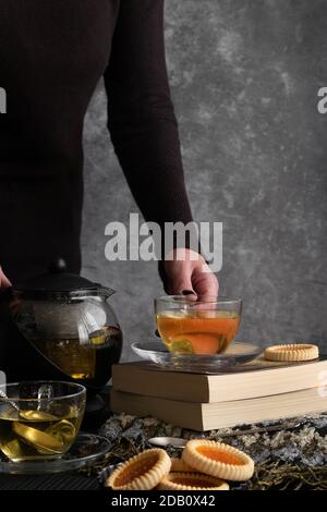 Frau Hände gießt Tee aus einer Teekanne Stockfoto