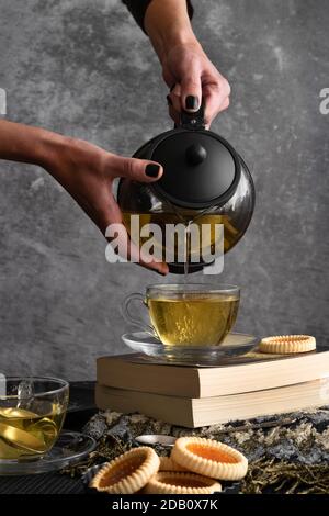 Frau Hände gießt Tee aus einer Teekanne Stockfoto