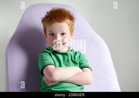 Niedlichen rothaarigen Sommersprossen kleinen Jungen in grünen T-Shirt warten Für Arzt in der Arztpraxis Stockfoto