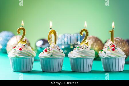 Goldene Kerzen in Form von Zahlen 2021 auf Cupcakes. Happy New Year, Frohe Weihnachten und Winter Season Greetings Konzept. Speicherplatz kopieren Stockfoto