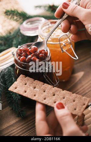 Weibliche Hände setzen Marmelade auf einem Knäckebrot Nahaufnahme. Weihnachtsfrühstück Stockfoto