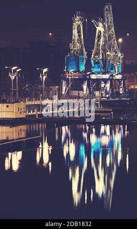 Beleuchtete Hafenkrane auf der Insel Lasztownia in Stettin bei nebliger Nacht, Farbtonung aufgetragen, Polen. Stockfoto