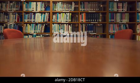 Ein Holzschreibtisch und Bücherregal im Bibliotheksraum, Bildungskonzept. Stockfoto