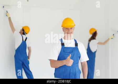 Arbeiter gibt Daumen nach oben vor zwei Maler Stockfoto