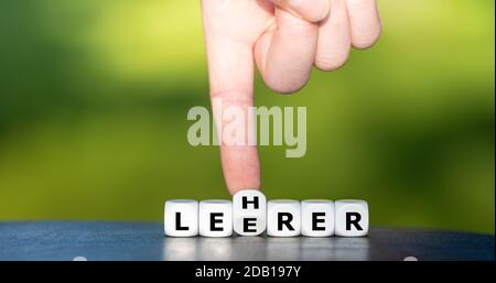 Hand dreht Würfel und ändert das deutsche Wort 'Leerer' (leer) in 'Lehrer' (Lehrer). Stockfoto