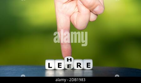 Hand dreht Würfel und ändert das deutsche Wort 'Leere' in 'Lehre'. Stockfoto