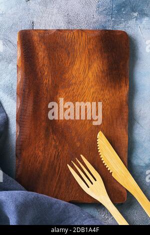 Leeres Holztablett und Besteck auf dem Tisch mit Kopierplatz, Draufsicht. Hintergrund für das Essen Stockfoto