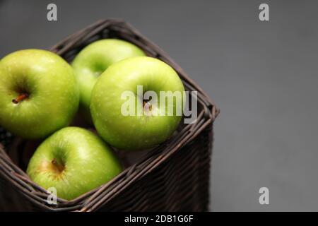 Fünf grüne Äpfel in einem Korb auf dunklem Grund Stockfoto