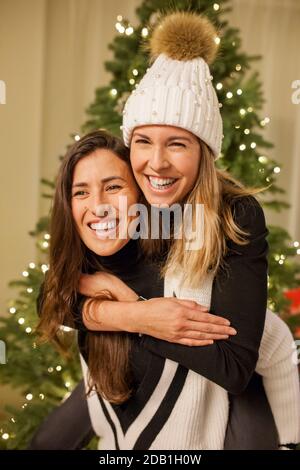 Zwei schöne lächelnde Mädchen feiern weihnachten mit einem weihnachtsbaum Hinter ihnen Stockfoto