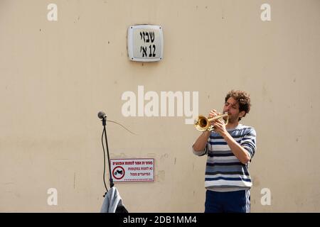 TEL AVIV, ISRAEL - 7. MÄRZ 2019: Urbane Szene. Straßenmusiker spielt Trompete in Neve Tzedek, historischem Viertel reich an Kunstgalerien, Boutiquen Stockfoto