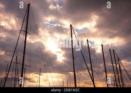 Segelboot Masten im Hafen bei Sonnenuntergang goldenes Licht vor Regensturm. Majestätische Natur Hintergrund. Maritime Reise- und Erlebniskonzepte. Stockfoto