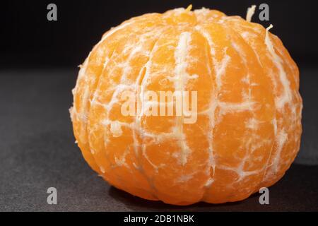 Geschälte Mandarine auf schwarzem Hintergrund. Nahaufnahme von tropischen Früchten aus biologischem Anbau. Stockfoto