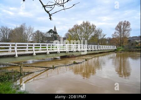 Alfriston Sussex UK 16. November 2020 - Wanderer überqueren eine Brücke über hohe Wasserstände am Fluss Cuckmere in Alfriston bei Seaford in East Sussex nach den jüngsten starken Regenfällen und ungewöhnlich hohen Gezeiten. Hochwasserwarnungen wurden in ganz Großbritannien nach dem jüngsten nassen Wetter ausgegeben, aber kältere Bedingungen werden für später in der Woche prognostiziert : Credit Simon Dack / Alamy Live News Stockfoto