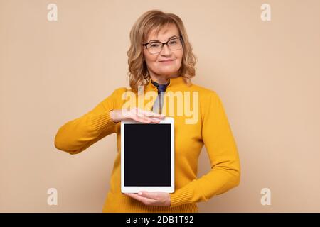 Senior Office Frau zeigt leeren Tablet-Bildschirm mit Copyspace Stockfoto