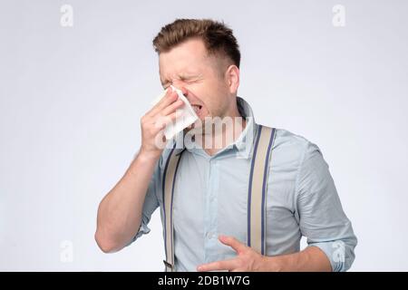 Junger Kaukasianer, der seine Nase mit einem niesen Taschentuch bedeckt. Stockfoto