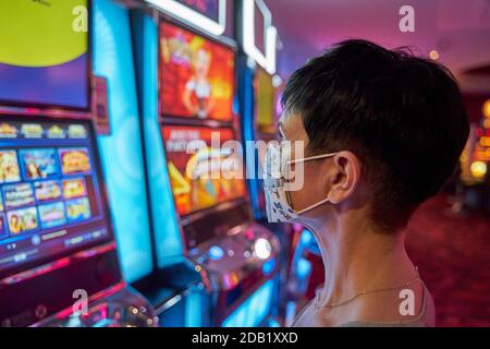 Schwarze kurzhaarige Hündin mit Covid Maske beim Spielen der Spielautomaten Stockfoto