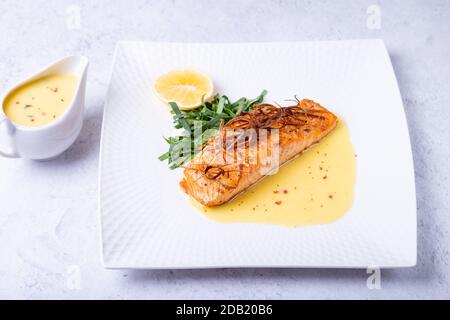 Lachs mit Beurre Blanc Sauce, Spinat und Zitrone. Garniert mit Lauch. Traditionelles französisches Gericht. Nahaufnahme. Stockfoto