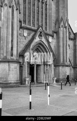 Maskierter Mann, der die Kirche mit einem Beerdigungskranz während der 19. Covid-Beschränkungen in der St Marys Kathedrale in Kilkenny, County Kilkenny, Irland, betritt Stockfoto