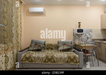 Fragment des Innenraums der Studio-Wohnung, neben dem Sofa befindet sich ein Esstisch Stockfoto