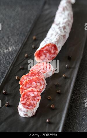 Fuet - Katalanische Trockenwurst auf dem schwarzen Servierplatte Stockfoto