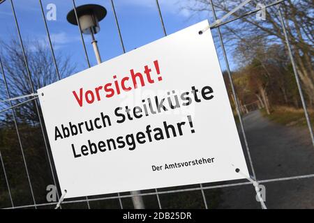 Stralsund, Deutschland. November 2020. Ein Schild mit den Worten 'Vorsicht! Abbruch steile Küste Gefahr für das Leben' hängt an einem Zaun. In der Nähe des Piers rutschte am 14.11.2020 ein großer Bereich des Abhangs ab. Nach Angaben der Gemeinde war dies eine Fläche von etwa 150 Quadratmetern. Erde und Bäume stürzten etwa 300 Meter nördlich des Piers ab und vergruben das Ende eines Strandweges. Quelle: Stefan Sauer/dpa-Zentralbild/dpa/Alamy Live News Stockfoto
