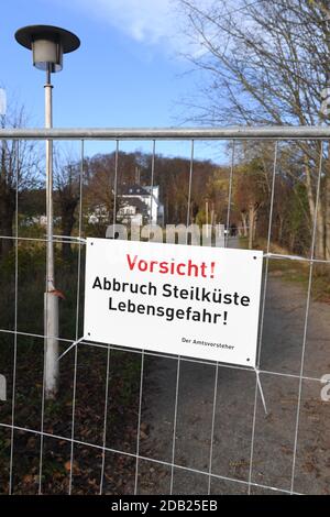 Stralsund, Deutschland. November 2020. Ein Schild mit den Worten 'Vorsicht! Abbruch steile Küste Gefahr für das Leben' hängt an einem Zaun. In der Nähe des Piers rutschte am 14.11.2020 ein großer Bereich des Abhangs ab. Nach Angaben der Gemeinde war dies eine Fläche von etwa 150 Quadratmetern. Erde und Bäume stürzten etwa 300 Meter nördlich des Piers ab und vergruben das Ende eines Strandweges. Quelle: Stefan Sauer/dpa-Zentralbild/dpa/Alamy Live News Stockfoto