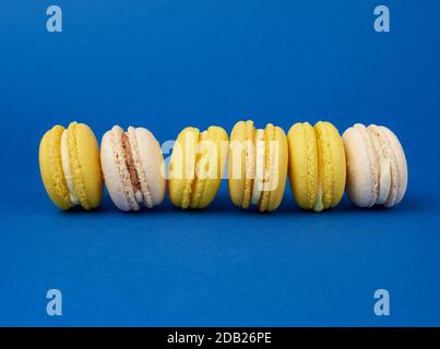 Bunte, runde, gebackene Makaronkuchen auf dunkelblauem Grund, Dessert liegt in einer Reihe, ganz in der Nähe Stockfoto