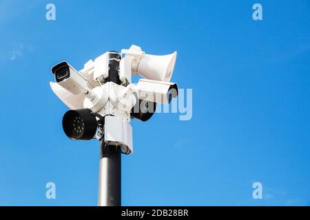 CCTV-Kameras, Leuchten und Lautsprecher sind an einem Mast unter blauem Himmel montiert Stockfoto