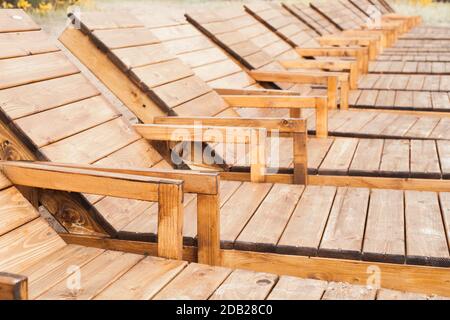 Leere hölzerne Sonnenliegen stehen in einer Reihe. Foto im Freien zur Ruhe Stockfoto