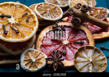 Getrocknete Orangen, Zitrone, Limette und Grapefruit mit Zimt, Anis und Nelken auf benzinfarbenem Holz. Stockfoto