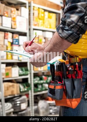 Elektrofachkraft im Elektrogerätelager schreibt auf dem Notebook. Bauindustrie, Elektrik. Stockfoto