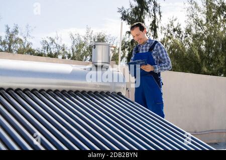 Klempner, Der Die Prüfung Des Solar-Energiekessels Durchgeführt Hat Stockfoto