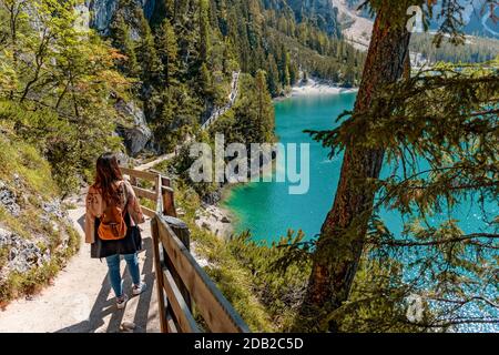 Rückansicht der jungen Frau, die auf dem Weg am grünen See in den Bergen läuft. Lake Prags, Italien. Stockfoto