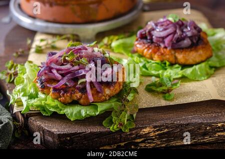 Köstliches Steak mit karamellisierter roter Zwiebel und frischen Kräutern auf Salat Stockfoto