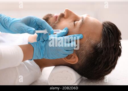 Kosmetologe macht Beauty-Injektionen für Mann mittleren Alters Stockfoto